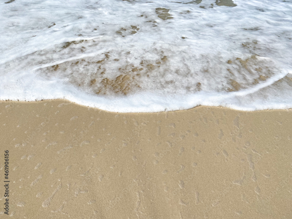 White sea wave foam crashing on clear wet sand on sea shore