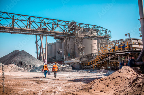 People are working in the industry. Modern technologies work at a cement plant. Technological work on the production of cement. Working atmosphere with copy space. Heaps of sand and soil raw materials photo