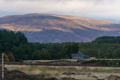 Stone cottage in front of mountain in golden sunlight in the Cairngorms National Park, Scottish Highlands, Scotland, UK