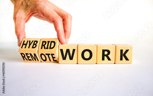 Hybrid or remote work symbol. Businessman turns cubes and changes words 'remote work' to 'hybrid work'. Beautiful white background. Business, hybrid or remote working concept, copy space. photo