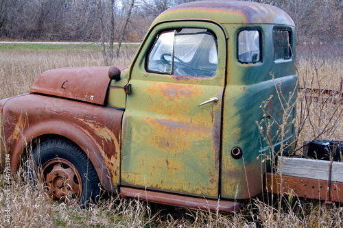 Green truck cab with rusted hood forgotten in a farmer's field. Ottertail Minnesota MN USA