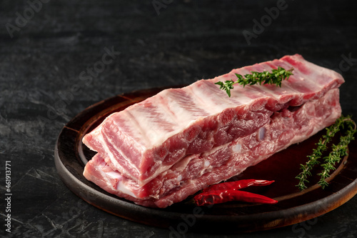 Raw pork ribs with spices and thyme on a dark wooden background