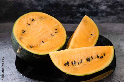 slices and half of a small yellow watermelon on a plate