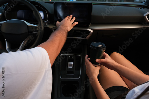 hand touching navigation dashboard inside car. Couple drinking coffee in the car