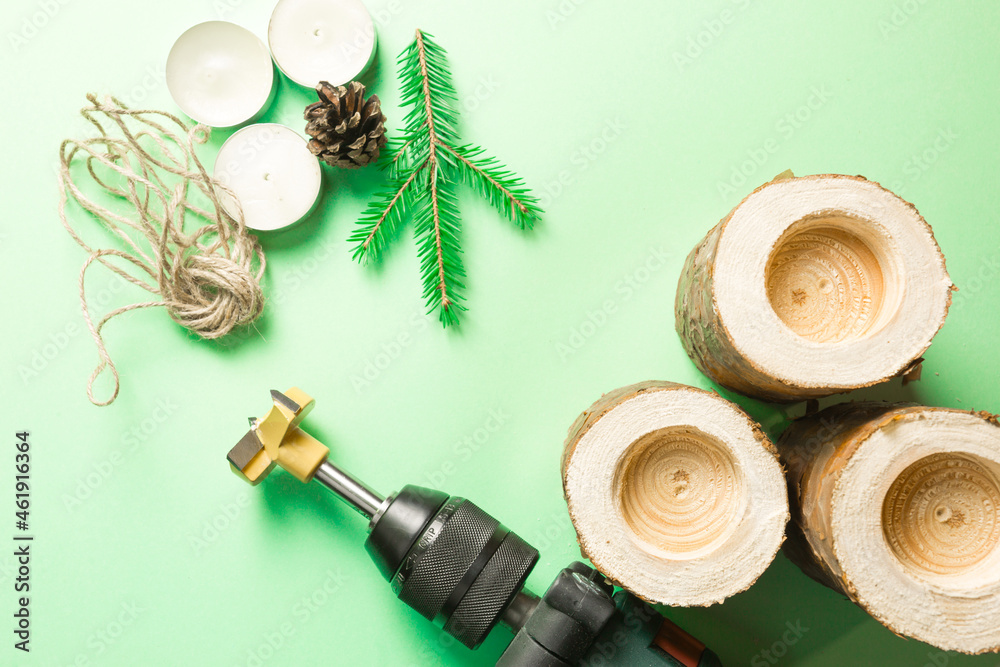DIY Christmas candle holder made of pine logs, candles, craft rope, fir branches and cones. A drill is a tool for manufacturing. Drill holes. Step-by-step instructions flat lay, step 2. DIY Christmas candle holder made of pine logs, candles, craft rope, fir branches and cones. A drill is a tool for manufacturing. Drill holes. Step-by-step instructions flat lay, step 2.