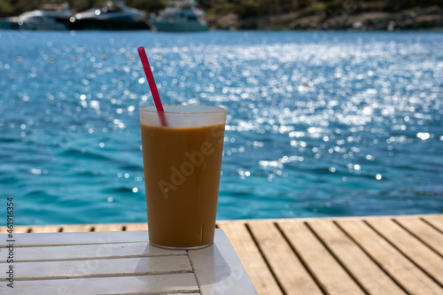 mug of cold coffee on wooden floor by the beach