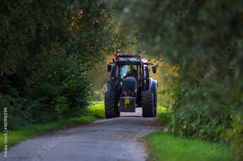 Duży traktor na drodze w alejce drzew