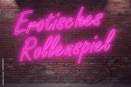 Neon erotic roleplay (in german Erotisches Rollenspiel) lettering on Brick Wall at night