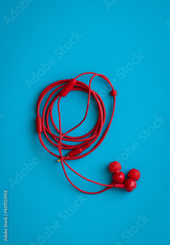 Red headphones with rolled wire, on a blue blbackground