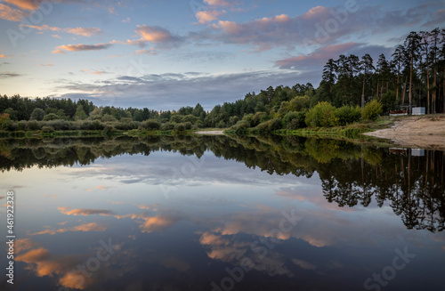 Fototapeta Naklejka Na Ścianę i Meble -  Summer landscape in the evening by the river. Dramatic clouds are reflected in the water. Intense colors in the landscape after sunset.