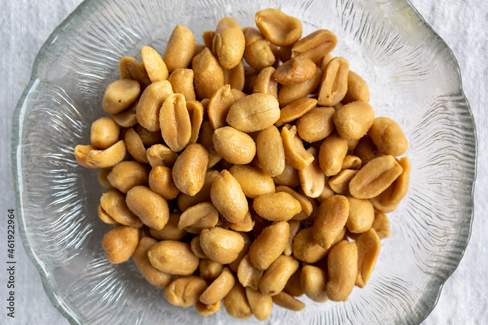 Close up of salted peanuts in a glass bowl. Overhead view with white background Close up of salted peanuts in a glass bowl. Overhead view with white background