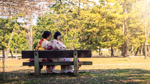 Maiko geisha sitting on the park bench of Nara. Tourits women in kimono at Japan