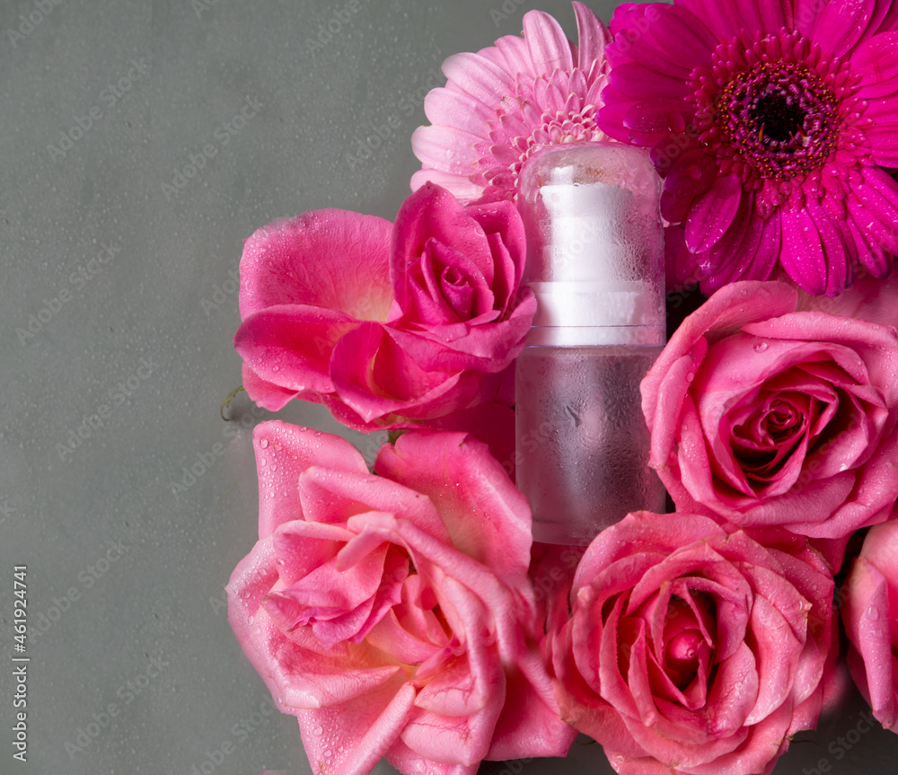 A glass jar for oil and cosmetics with on a green background of pink fluffy flowers. Mockup of cosmetics and silk plants. A glass jar for oil and cosmetics with on a green background of pink fluffy flowers. Mockup of cosmetics and silk plants.