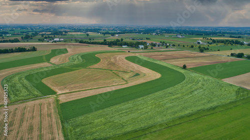 A Beautiful Aerial View of Farm Countryside with Patches of Colored Fields with White Fully Clouds and Shadows photo