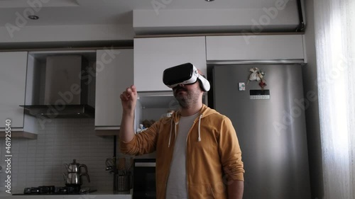 Young man walking around virtual market with vr glasses in kitchen. Young man buying kitchen necessities in the virtual world.