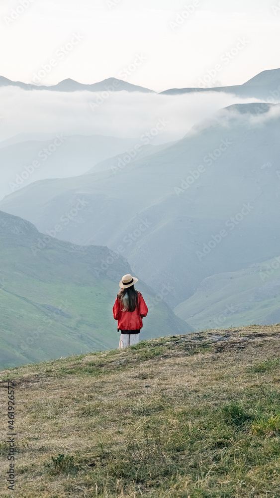 Teenage girl in a hat walks in the picturesque mountains. Wanderlust and travel concept. Beautiful nature landscape