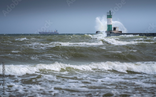 giant wave and water drops on lighthouse in storm sea