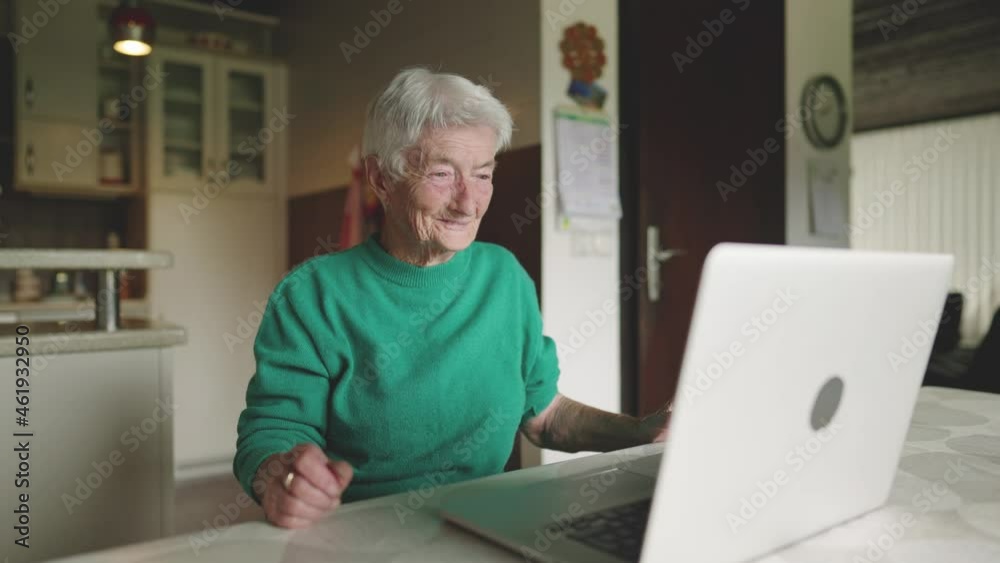 Slow motion - Old female behind the computer laughing and talking on a video cal Slow motion - Old female behind the computer laughing and talking on a video cal