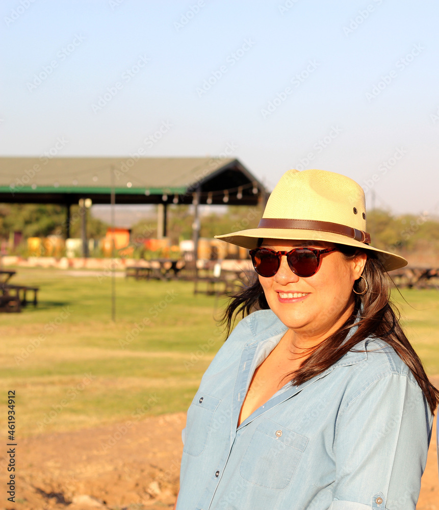 Latin adult woman with sunglasses and hat enjoys the sunset in an outdoor park relaxed, happy and calm
Latin adult woman with sunglasses and hat enjoys the sunset in an outdoor park relaxed, happy and calm