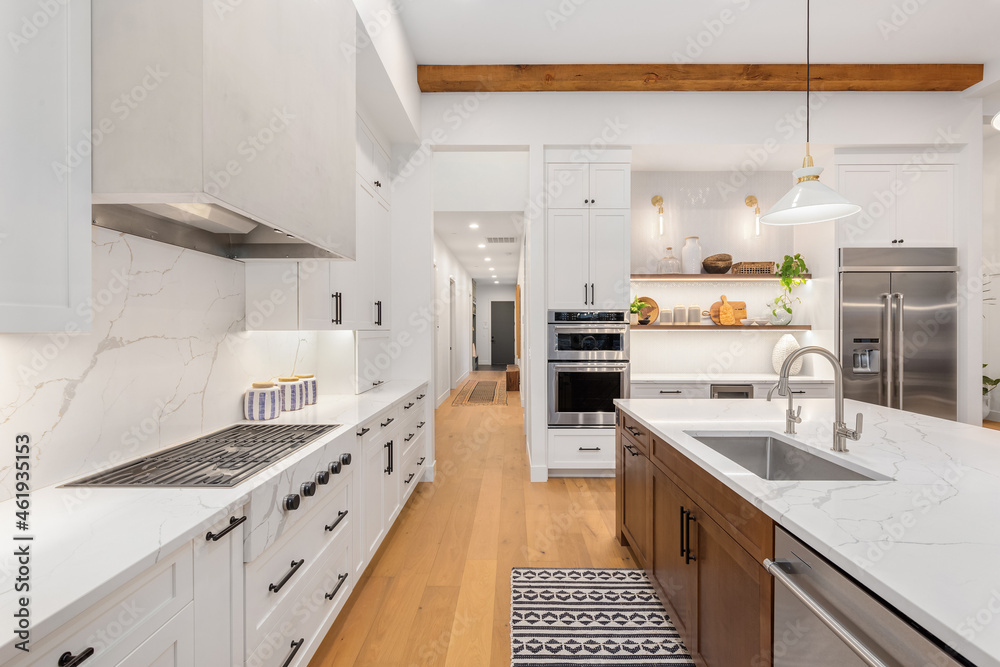 Beautiful white kitchen in new luxury home with large island. Features large island, stainless steel appliances, and sleek modern range hood. Beautiful white kitchen in new luxury home with large island. Features large island, stainless steel appliances, and sleek modern range hood.