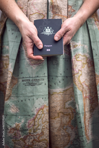 A close up of hands holding an Australian passport in front of a map fabric dress