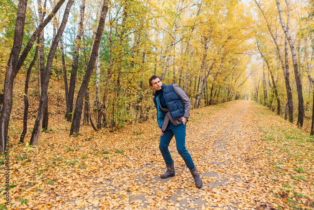 Tall handsome man walking in the autumn alley