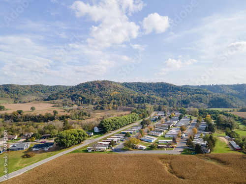 rural neighborhood and farm land in autumn in midwest  mountains with trees and open landscape  farm fields after harvest  family friendly single-family homes and mobile home park for diversity.   