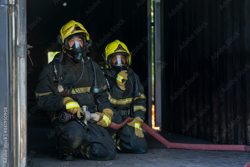 Firefighter in fire fighting operation,Fireman using water and extinguisher to fighting with fire flame in an emergency situation.