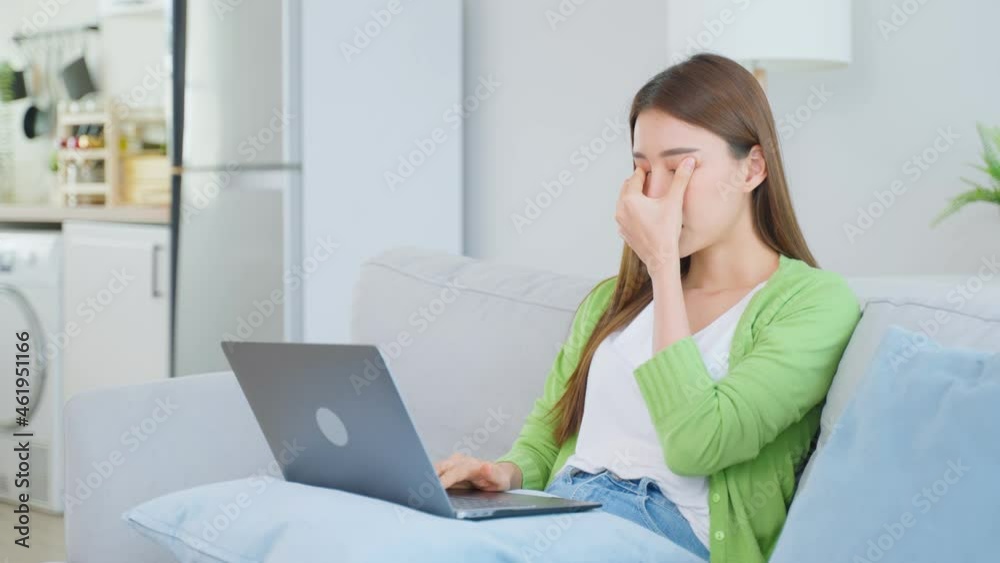Exhausted Asian business woman hurt eye while using laptop computer.