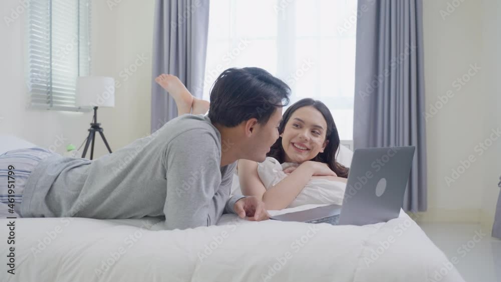 Asian young couple lying down on bed use laptop watch movie in bedroom. Asian young couple lying down on bed use laptop watch movie in bedroom.