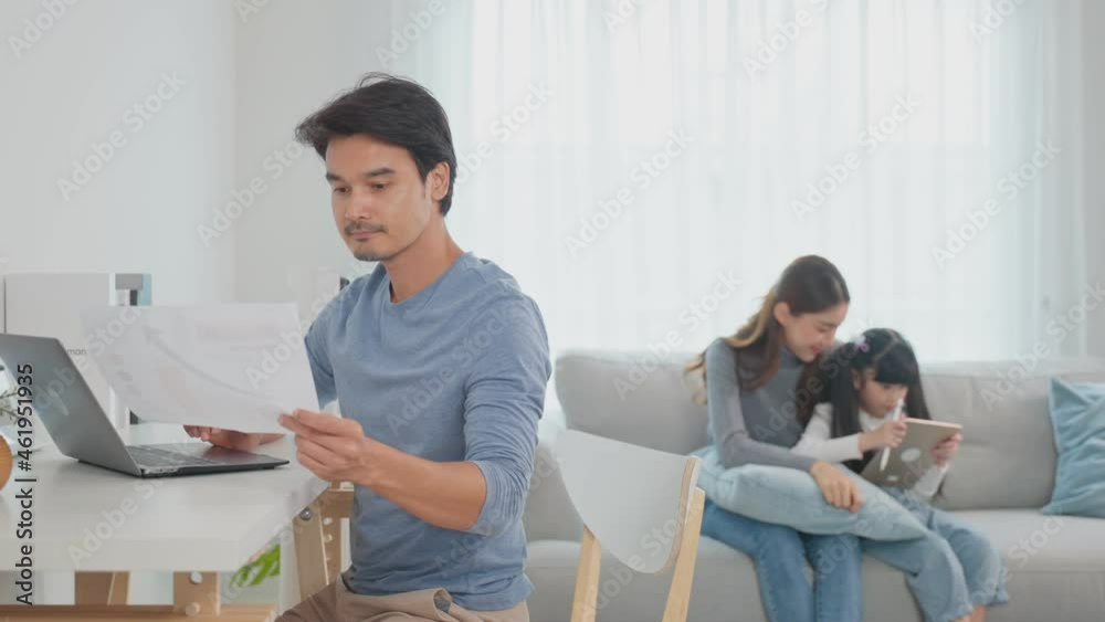 Asian business man father sit on table work at home with family behind. Asian business man father sit on table work at home with family behind.