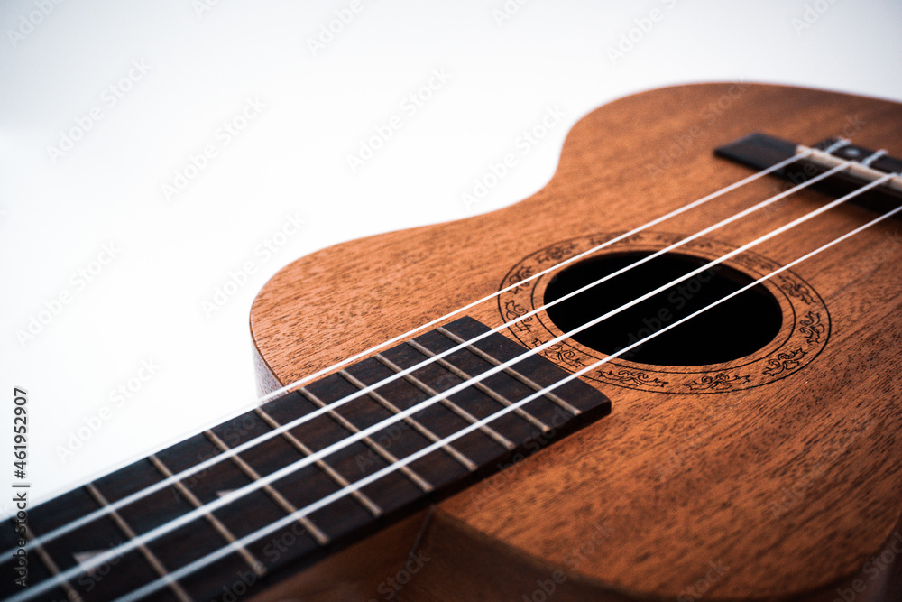 Obraz premium Close up of brown Ukulele on white background. Ukulele strings, saddle, soundhole, ukulele body, neck, fretboard.