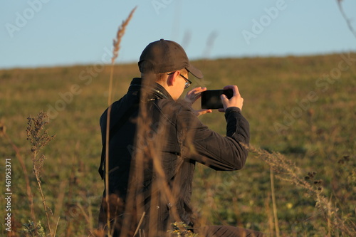 Young man photographs a field in autumn, autumn nature. Photographer in nature.