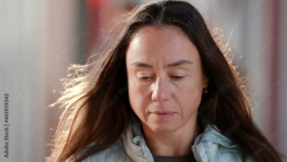 Close-up of the face of an adult woman on the street during the day is sad and looks down. Portrait of a woman without makeup natural beauty Close-up of the face of an adult woman on the street during the day is sad and looks down. Portrait of a woman without makeup natural beauty