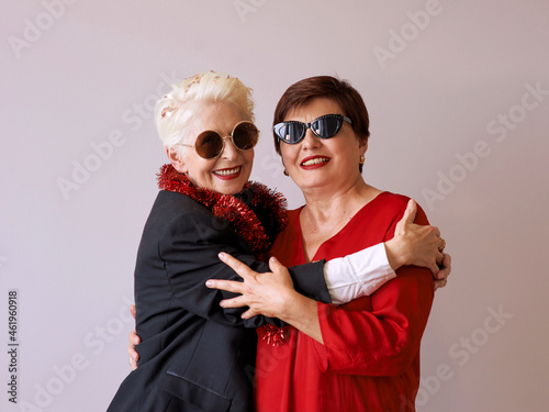 Two beautiful stylish mature senior women in sunglasses hugging. Fun, party, style, celebration concept