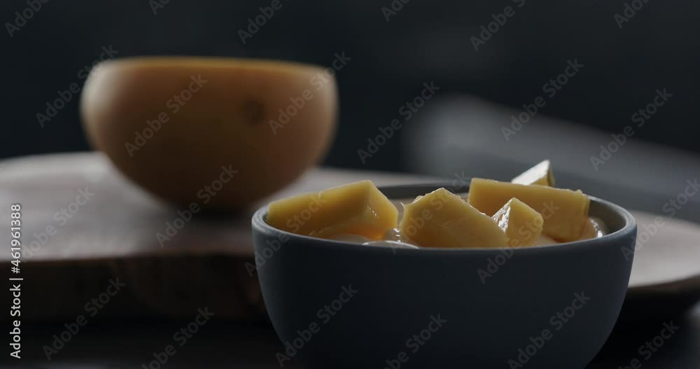 Slow motion put fresh thai mango in natural organic yogurt in blue bowl Slow motion put fresh thai mango in natural organic yogurt in blue bowl