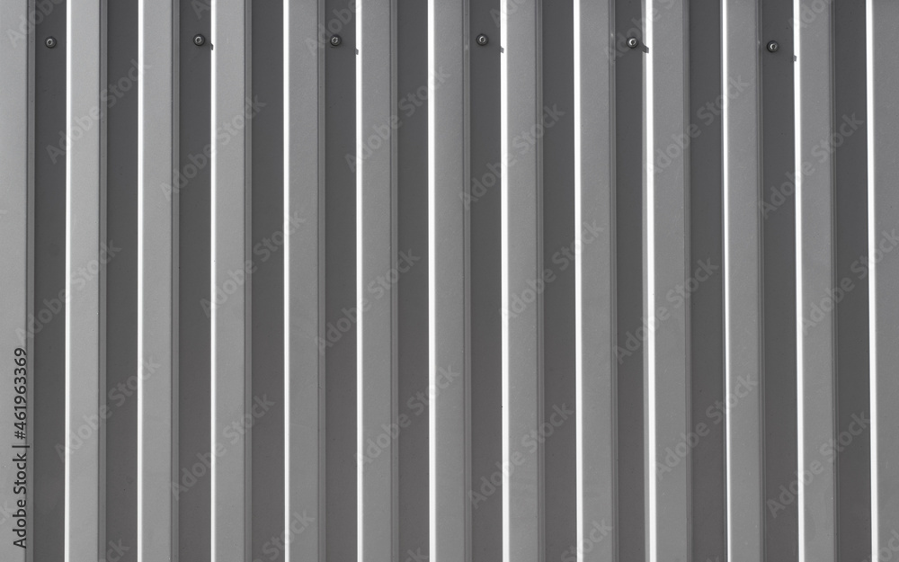 Iron construction gray profiled sheet screwed to wall. Facing or roofing building material. Textured uneven steel background, copy space for your text