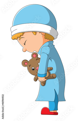 The sleepy boy is standing and holding the doll