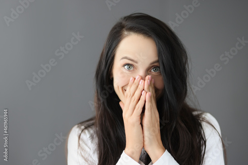 Portrait of smiling young woman covering nose with hand photo