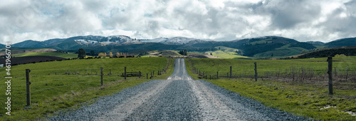 Rural gravel road on a farm, beautiful view of the snowy hills. New Zealand, canterbury
