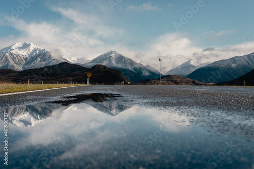 Snowy peaks reflected on a puddle from the road. Canterbury, New Zealand