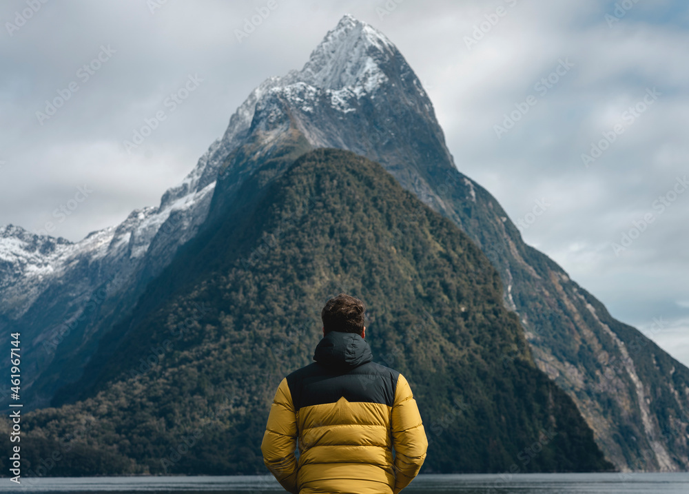 Man looking backwards at the majestic fjord in Milford Sound, New Zealand
