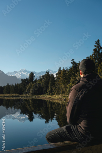 Man looking at mountains in Lake Matheson. New Zealand, South Island