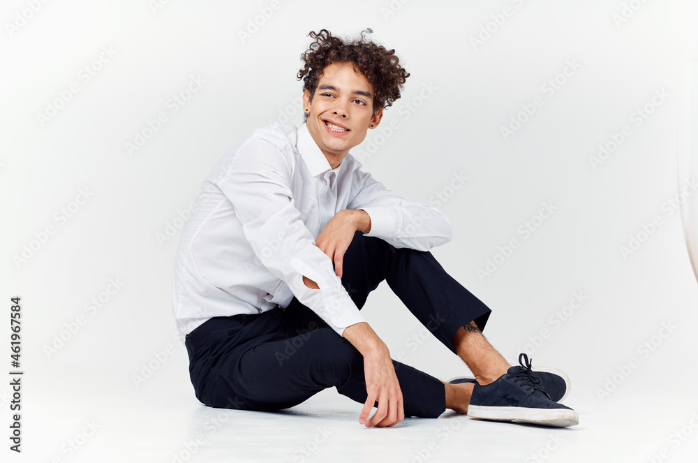 guy in a white shirt sitting on the floor curly hair fashion