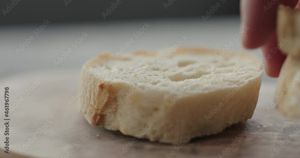 Slow motion put fresh baguette slice on olive board closeup