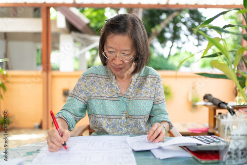 senior asian woman calculate income and expense balance at home terrace