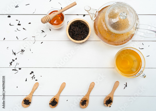 flat lay of hot tea in teapot and cup with honey on whote table