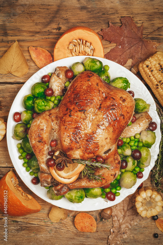 Thanksgiving turkey or chicken for a festive dinner. Food table background with autumn seasonal specialties for Thanksgiving Day. Fried chicken with pumpkin, vegetables and autumn decor on a wooden