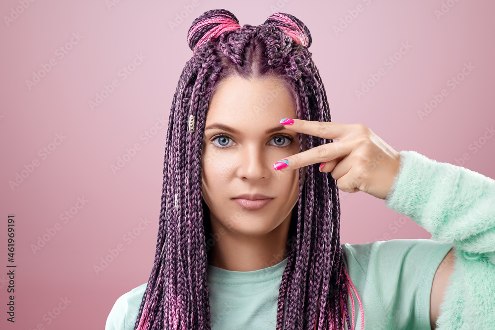 Portrait of a beautiful girl with a hairstyle of pink braids in turquoise clothes posing on a pink background in the studio. The concept is modern style, individuality, inclusiveness, creativity. Portrait of a beautiful girl with a hairstyle of pink braids in turquoise clothes posing on a pink background in the studio. The concept is modern style, individuality, inclusiveness, creativity.