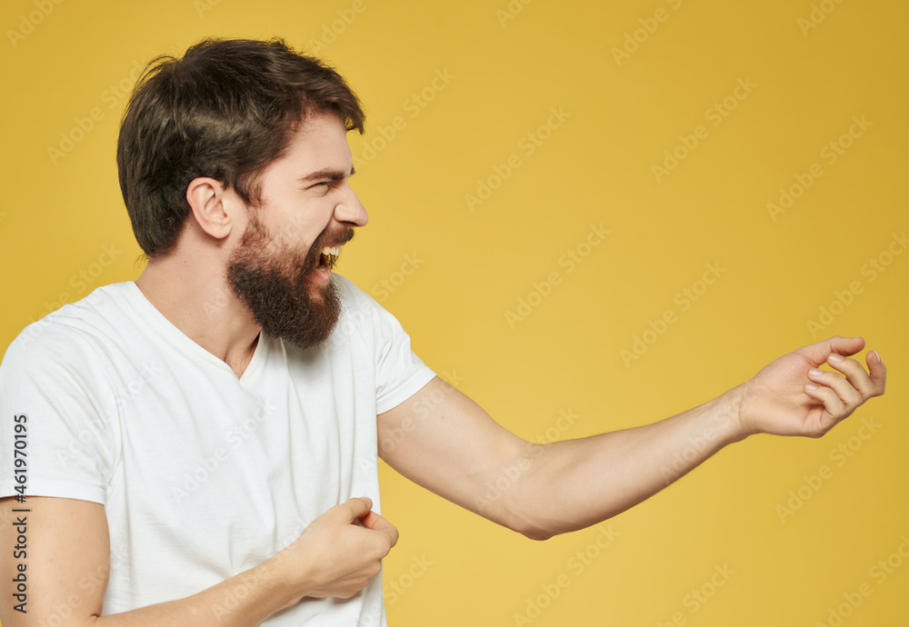 Man in a white t-shirt hand gestures anger yellow background Man in a white t-shirt hand gestures anger yellow background